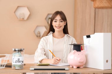 Evde deftere yazı yazan bir kız öğrenci. Eğitim tasarruf kavramı