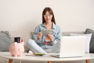 Parası olan bir kız öğrenci evdeki kanepede oturuyor. Eğitim tasarruf kavramı