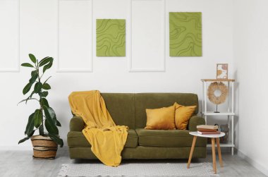 Koltuk, raf ünitesi, sehpa ve ev bitkisi oturma odasının içinde.