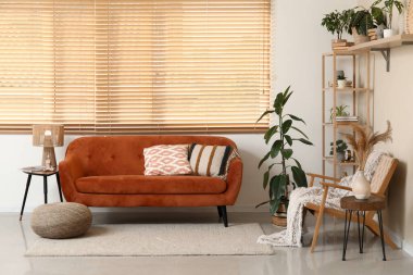 Oturma odasının içinde rahat bir kanepe, sandalye ve çiçek var.