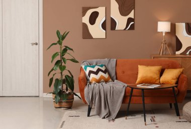 Turuncu kanepeli, kahve masalı ve çiçekli şık bir oda.