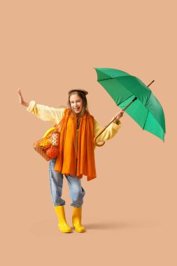 Kahverengi arka planda yeşil şemsiyeli ve sicim çantalı tatlı genç kız.