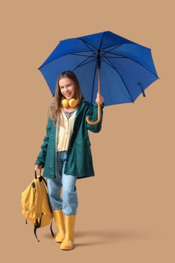 Mavi şemsiyeli, kulaklıklı ve kahverengi çantalı tatlı bir genç kız.