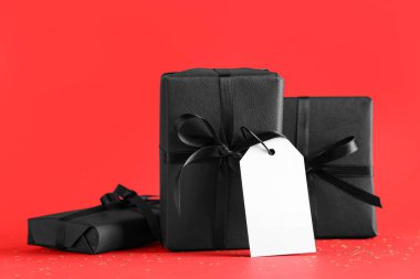 Kırmızı arka planda siyah hediye kutuları ve konfeti.