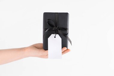 Gri arka planda siyah hediye kutusu olan bir kadın el.