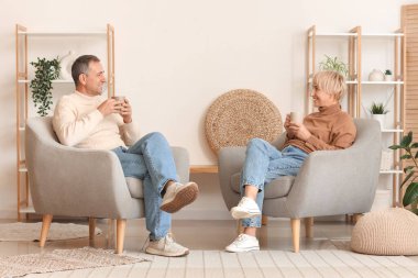 Evdeki koltuklarda oturan çay fincanları olan yaşlı çift.