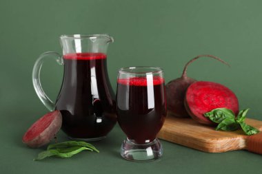 Yeşil arka planda fesleğen ve bir sürahi taze pancar suyu.