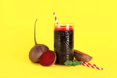 Sarı arka planda fesleğenli ve sebzeli taze pancar suyu.