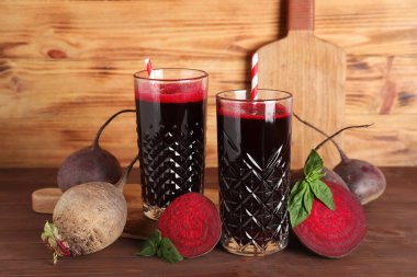 Tahta arka planda fesleğenli ve sebzeli taze pancar suyu.