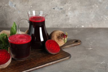 Gri arka planda fesleğenli bir bardak taze pancar suyu.