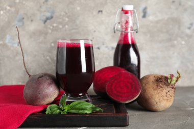 Gri arka planda fesleğen ve bir şişe taze pancar suyu.