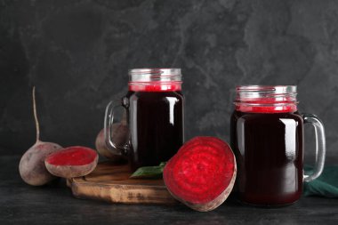 Mason kavanozları taze pancar suyu, fesleğen ve siyah arka planda sebze.