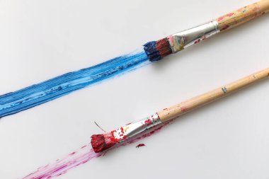 Beyaz arkaplanda boya darbeleri olan sanatçı fırçaları
