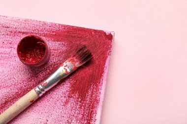 Pembe arka planda sanatçı fırçası, boya ve tuval, yakın plan