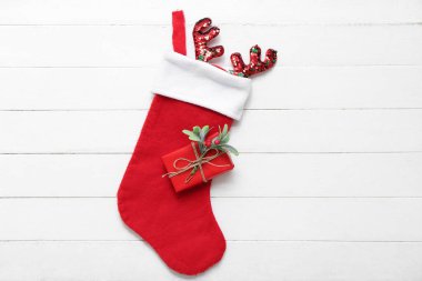 Ren geyiği boynuzları, hediye kutusu ve beyaz ahşap arka planda ökseotu dallı Noel çorabı. Üst görünüm