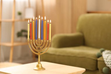 Menorah with burning candles on table at home, closeup. Hanukkah celebration clipart