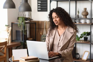 Kafedeki masada dizüstü bilgisayar kullanan genç bir Afro-Amerikalı yazar.