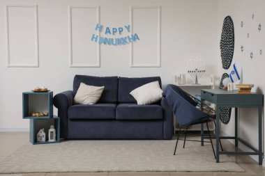 Interior of festive living room with stylish sofa, menorah and HAPPY HANUKKAH letter garland clipart