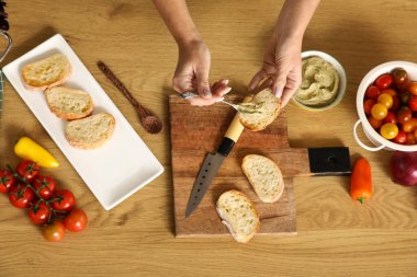 Genç bir kadın bruschetta 'nın üzerine vegan sosu döküyor.