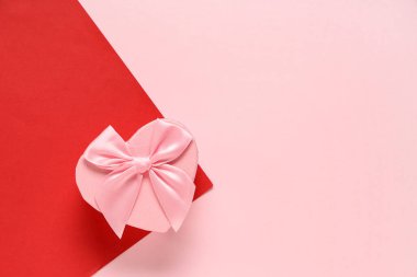 Renkli arka planda kalp şeklinde bir hediye kutusu. Sevgililer Günü kutlaması