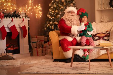 Noel Baba ve Noel arifesinde evde bir bardak sütle küçük şirin bir elf.