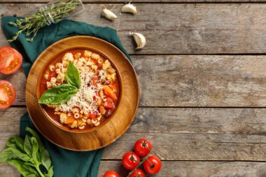 Bir kase peynirli makarna ve ahşap arka planda malzemeler.