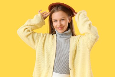 Cute girl in autumn clothes on yellow background clipart