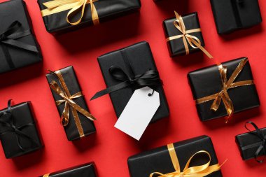 Kırmızı arka planda boş karton etiketli hediye kutuları. Kara Cuma indirimi