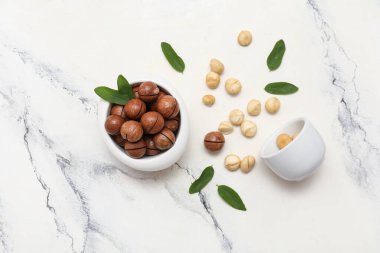 Lezzetli fındıklı kaseler ve beyaz arka planda yapraklar.