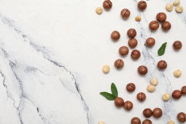 Beyaz arka planda yaprakları olan lezzetli Macadamia fındıkları.