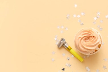 Parti düdüğü ve bej arka planda konfeti olan tatlı doğum günü keki.