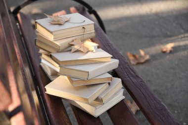 Parktaki bankta sonbahar yapraklı kitap yığını, yakın plan.