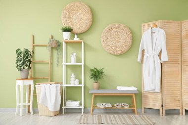 Rafları, terlikleri ve gri bankları olan şık bir banyo.