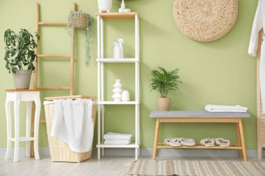 Rafları, terlikleri ve gri bankları olan şık bir banyo.