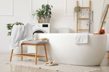 Banyonun içinde küvet ve gri bank var.