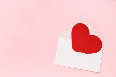 Pembe arka planda kırmızı kağıt kalpli zarf. Sevgililer Günü kutlaması