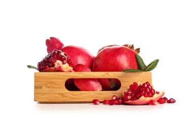 Tahta tepside taze nar ve beyaz arka planda yapraklar.