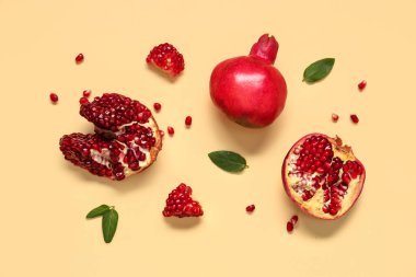 Sarı zemin üzerinde tohum ve yapraklarla taze olgun narlar.