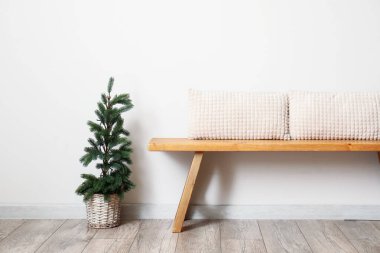 Yastıklı ahşap bank ve ışık duvarının yanındaki Noel ağacı.