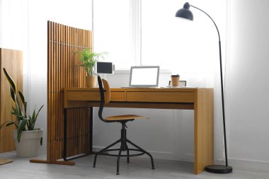 Dizüstü bilgisayarı, bir fincan kahvesi ve pencerenin yanında katlanan ekranı olan modern bir iş yeri.