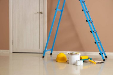 Boya kutuları ve bej duvarın yanındaki aletlerle merdiven.