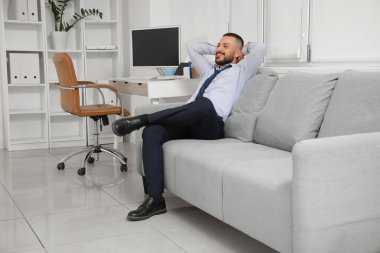 Kanepede hafta sonları ofiste bekleyen genç bir işadamı.