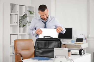 Genç işadamı izin gününden önce bilgisayarı çantaya koyuyor.