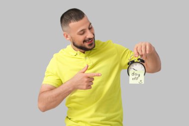 Gri arkaplana karşı alarmlı saat kapalı metin ile yapışkan nota işaret genç adam