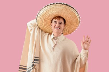 Pançolu genç Meksikalı adam portresi ve pembe arka planda şapka.