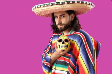 Mor arka planda boyalı kafatası olan yakışıklı bir Meksikalı. Ölüler Günü Kutlaması