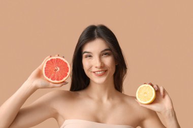 Gri arkaplanda greyfurt ve limon olan güzel genç bir kadın.