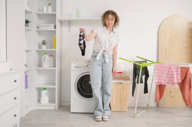 Çamaşır odasında kokuşmuş çorapları olan hoşnutsuz genç bir kadın.