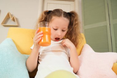 Şirin küçük kız evdeki koltukta tişörtüne meyve suyu döktü.