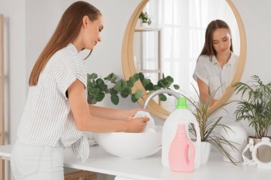 Evdeki lavaboda giysilerdeki lekeleri çıkaran genç bir kadın.